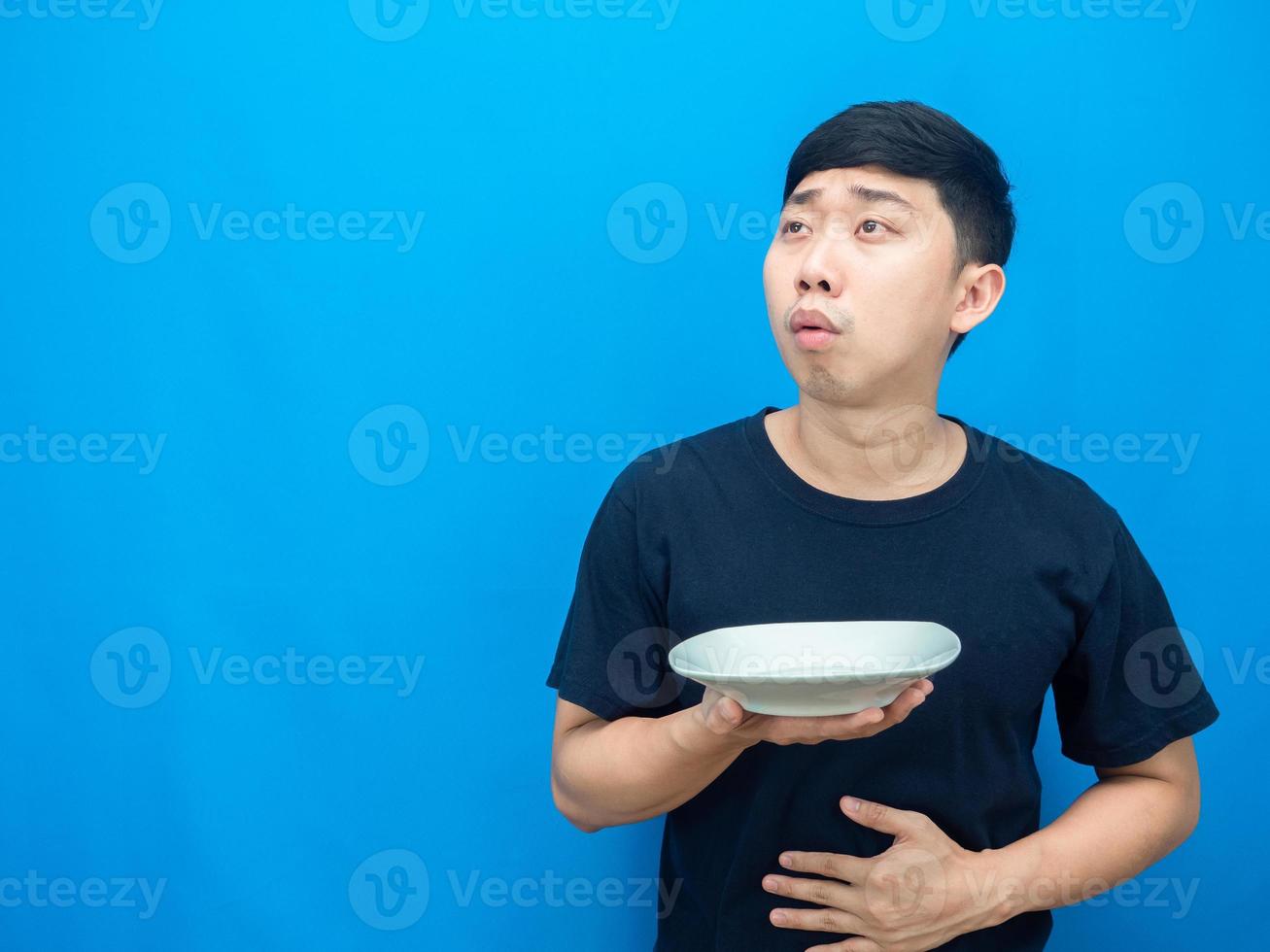 Man feeling hungry holding dish and looking at copy space thiking about dinner photo