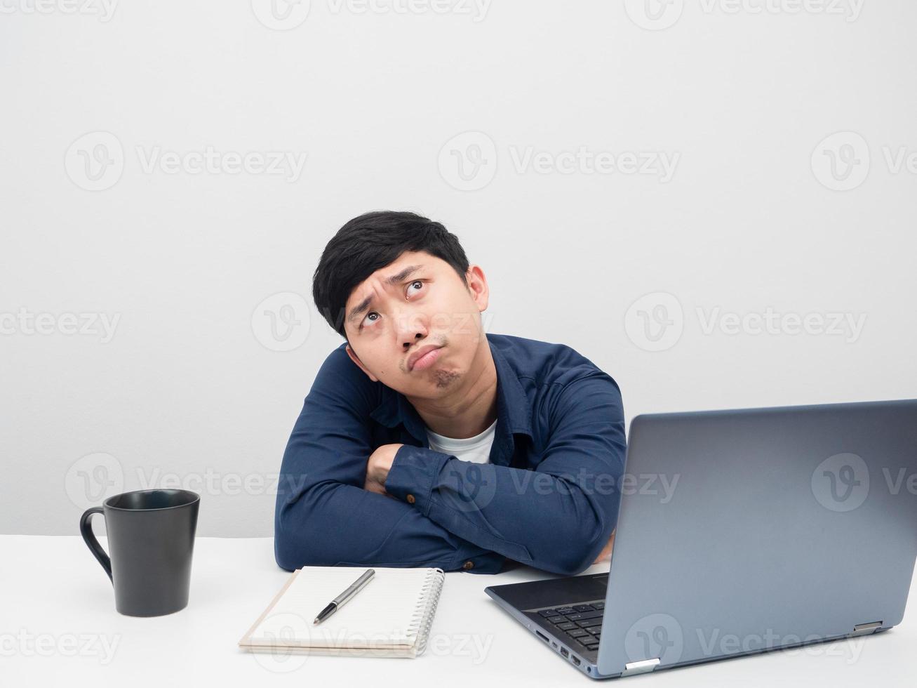 Man sit at the desk with workolace feeling bored and looking up photo