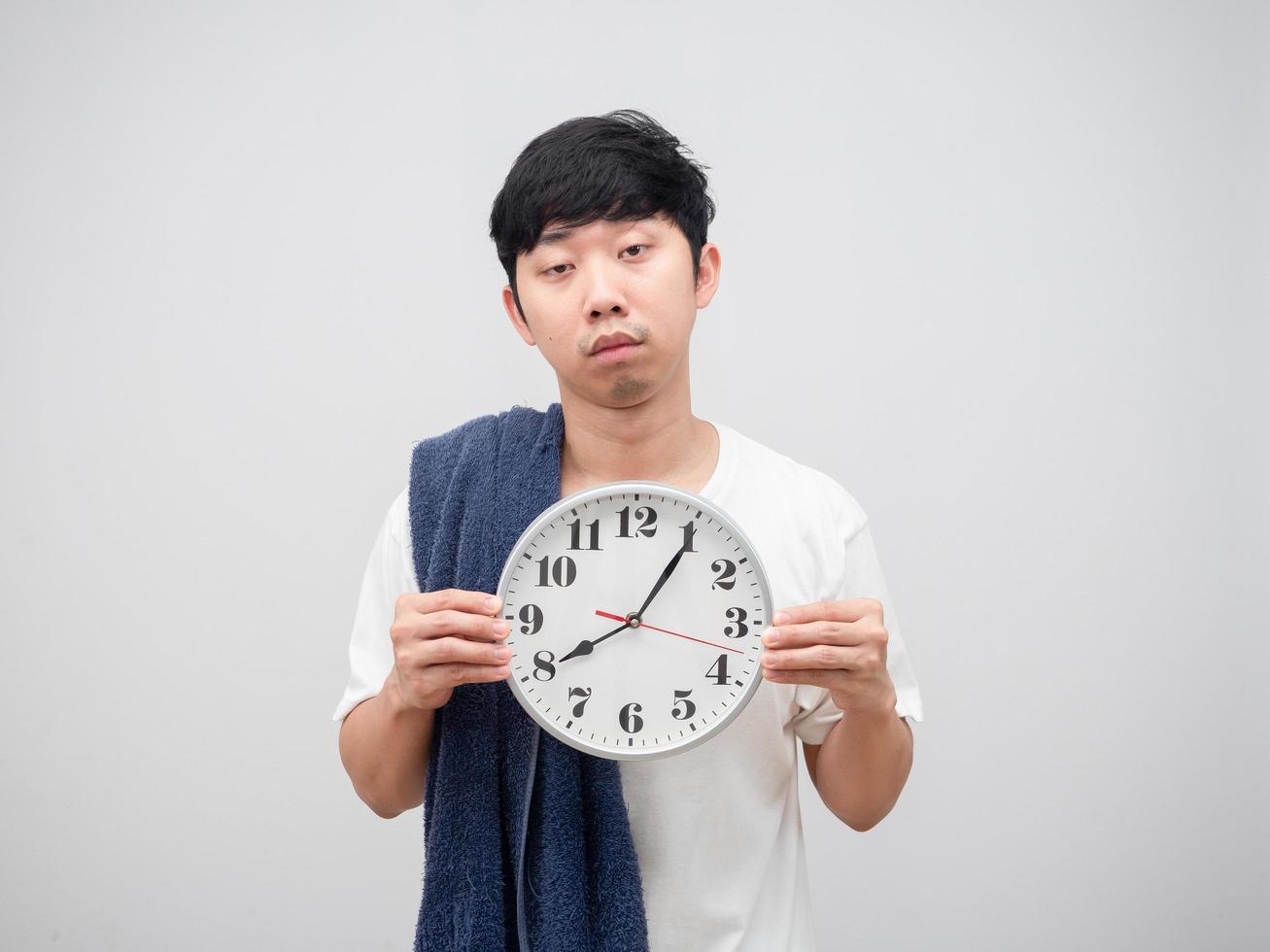 Asian man with towel holding clock sleepy face on white background photo