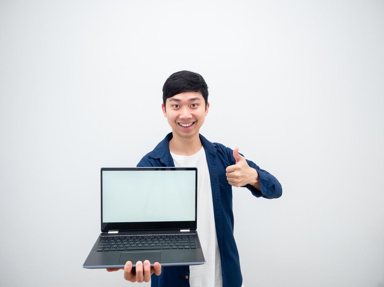 Asian cheerful man show laptop white screen in hand and thumb up looking at camera on white isolated background photo