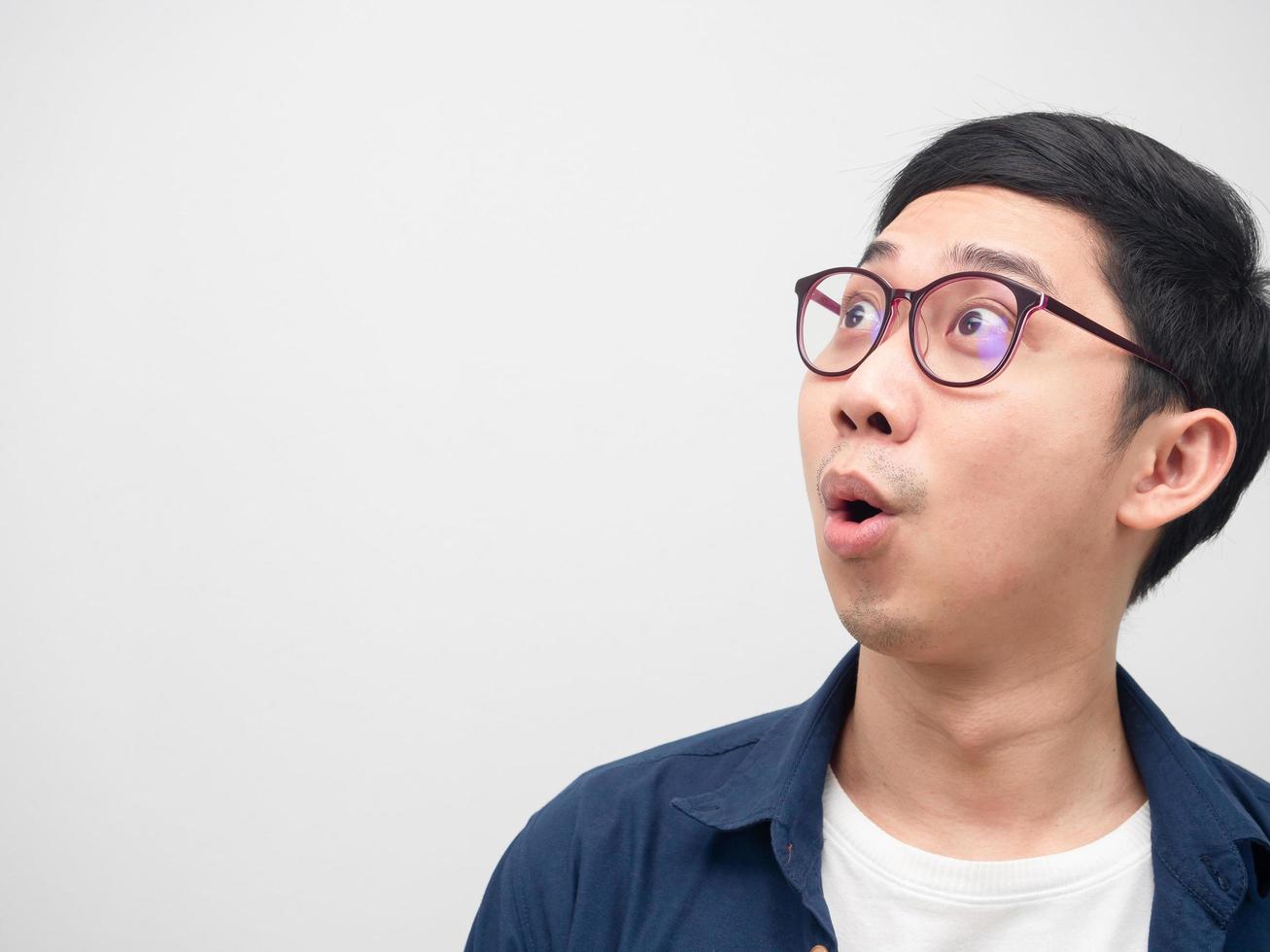 Close up face of asian man wearing glasses feeling amazed looking at copy space white background photo