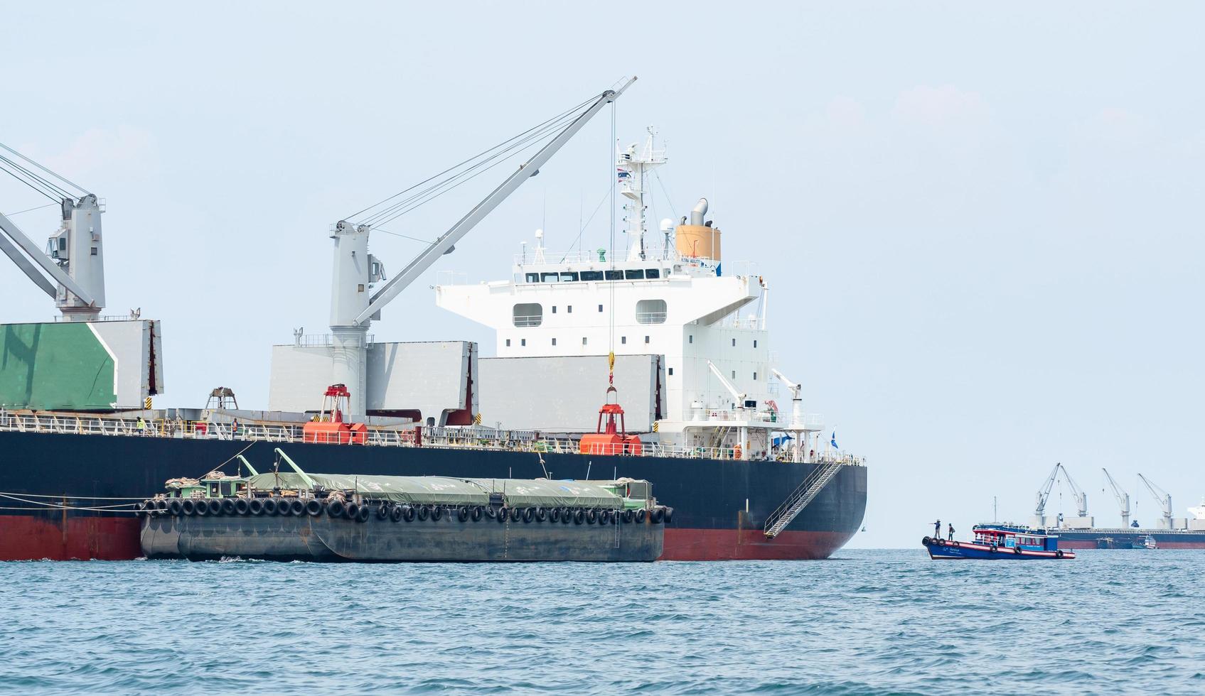 grúa en el barco industrial en el agua azul del océano y el paisaje del cielo azul, logística y concepto de barco de transporte en el mar foto