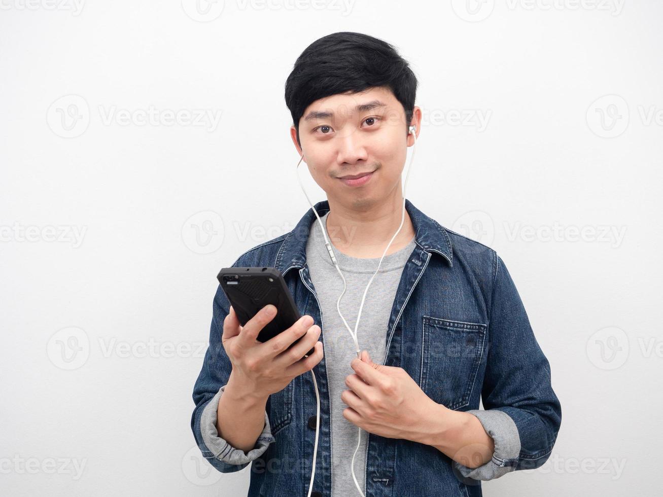 Man jeans shirt holding mobile phone using earphone portrait photo