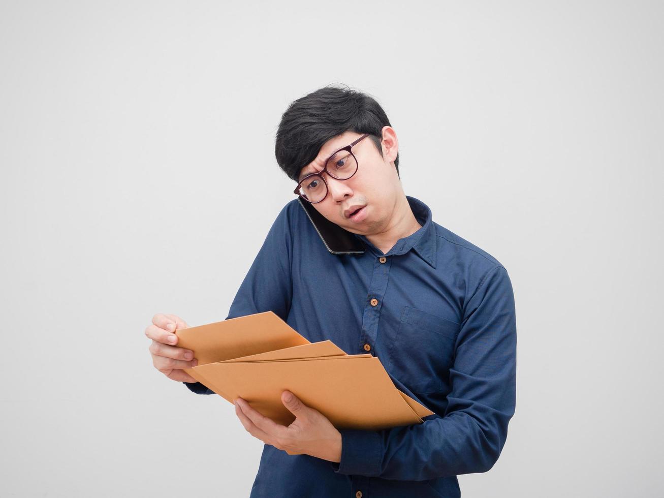 Asian man with glasses busy talking mobile phone and finding document envelope in his hand on white background photo