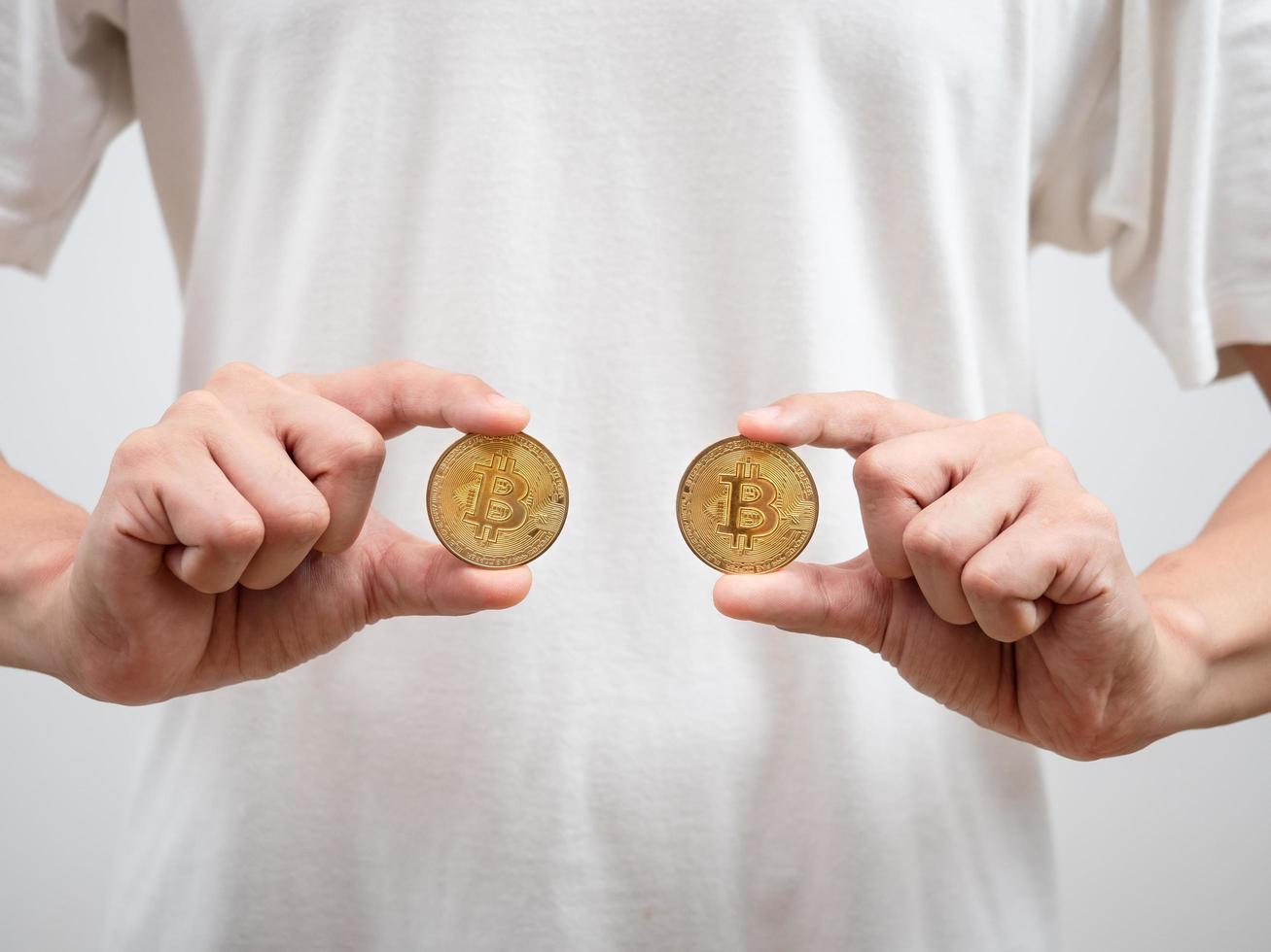 primer plano hombre camisa blanca mostrar bitcoins dorados en su mano foto