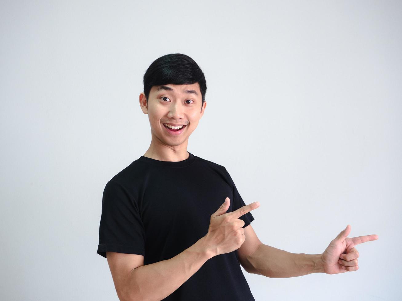 Cheerful asian man point double finger at right side on white wall background portrait photo