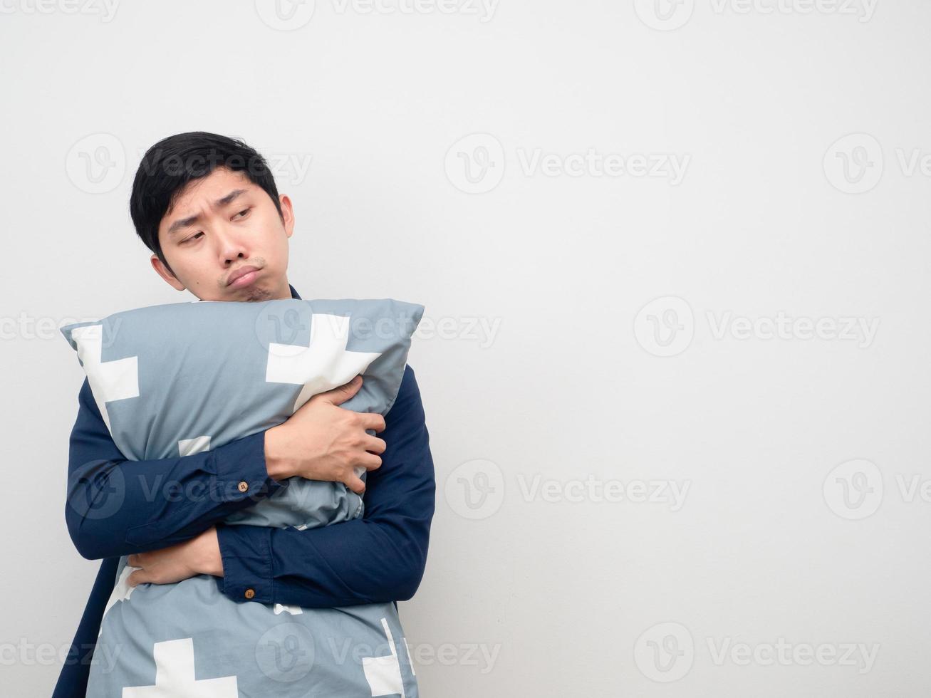 hombre asiático abraza la almohada con sueño y aburrido mirando el espacio de la copia foto