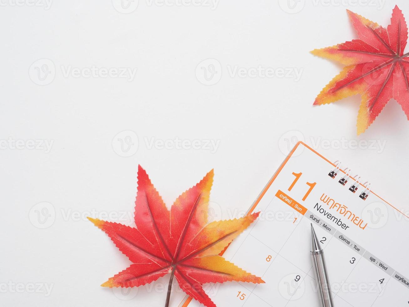 Close up pen on calendar with maple lead top view white background copy space autumn concept photo