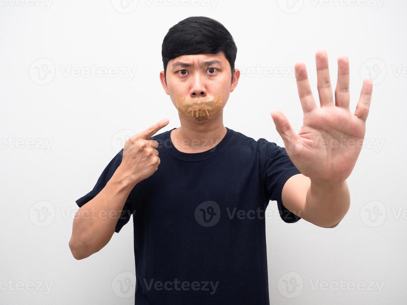 Man with tape close mouth point finger at mouth show hand stop isolated photo