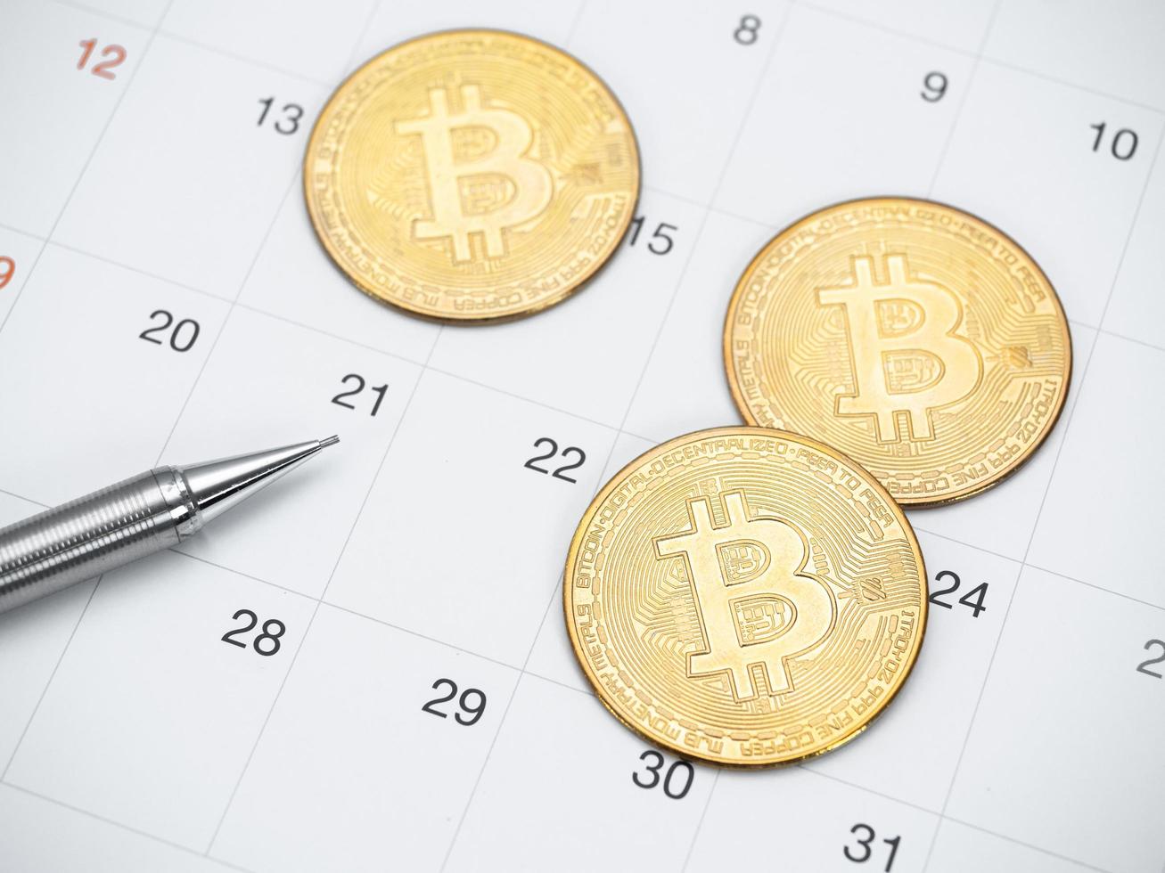 Closeup golden bitcoin and pen on calendar top view photo