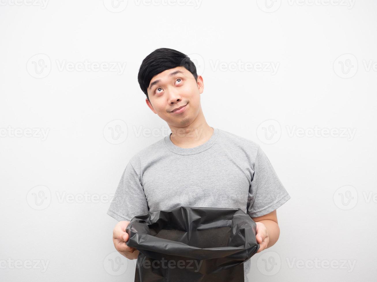 Asian man holding garbage and looking above photo