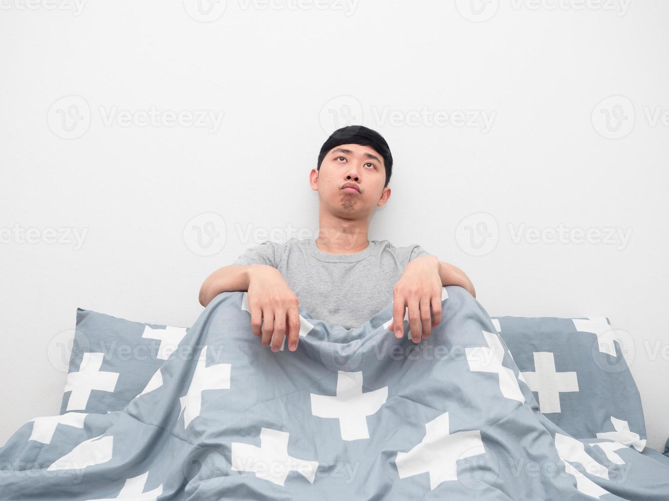 Asian man sitting on the bed bored emotion looking at copy space photo