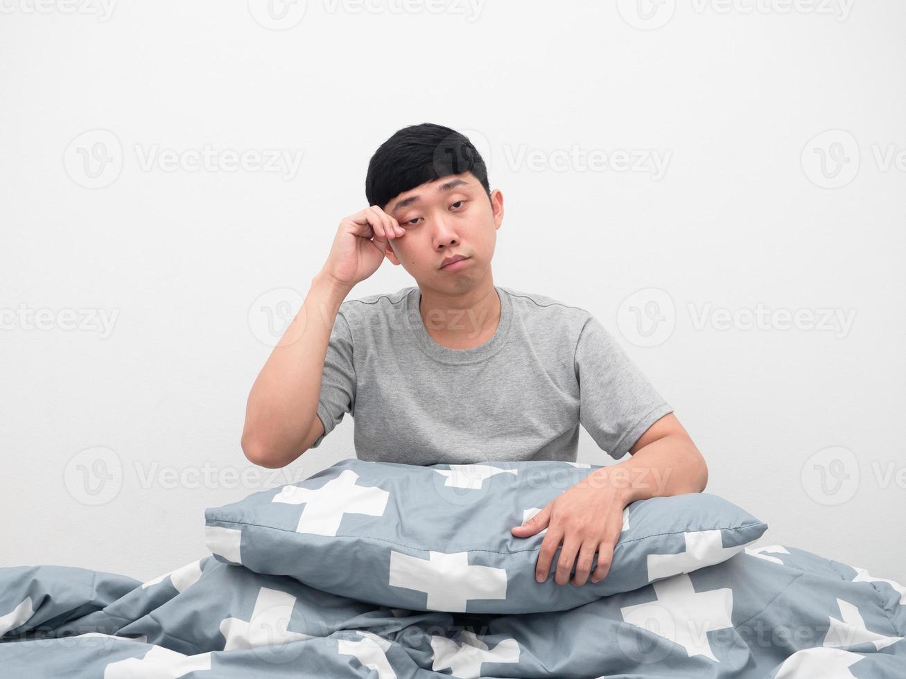 hombre sentado en la cama con gesto de almohada somnoliento foto