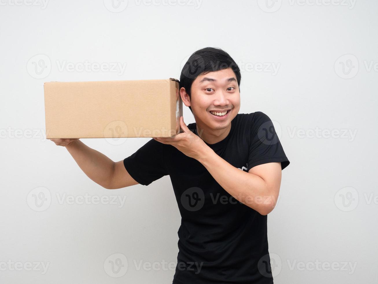 hombre sosteniendo una caja y escuchándola sintiéndose emocionado con la caja foto