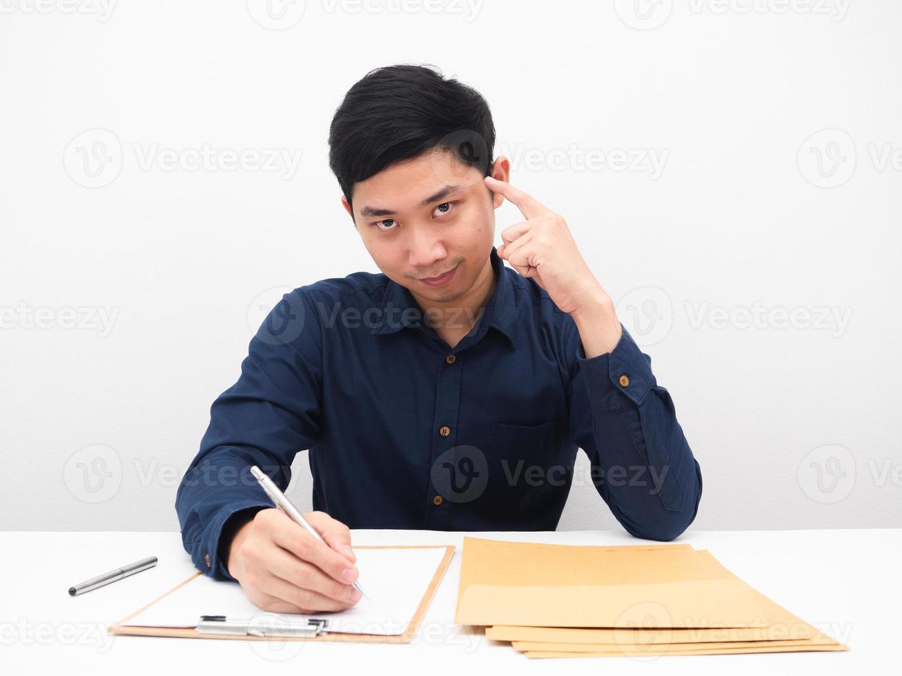 Asian man writing document on table and point finger at his head for thinking concept photo