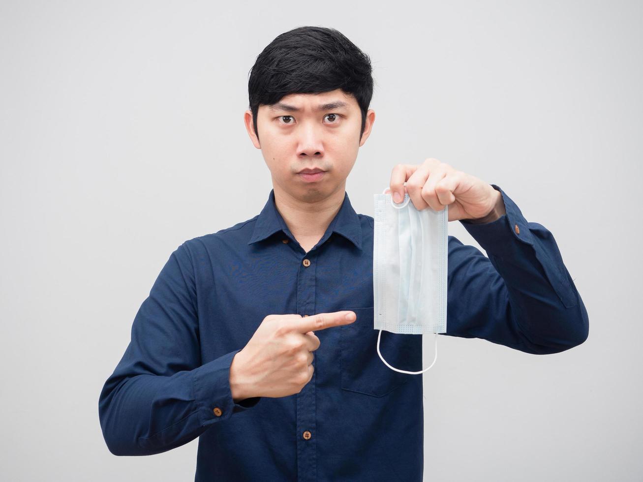 Asian man serious face point at protect mask in his hand prevent the virus concept white background photo