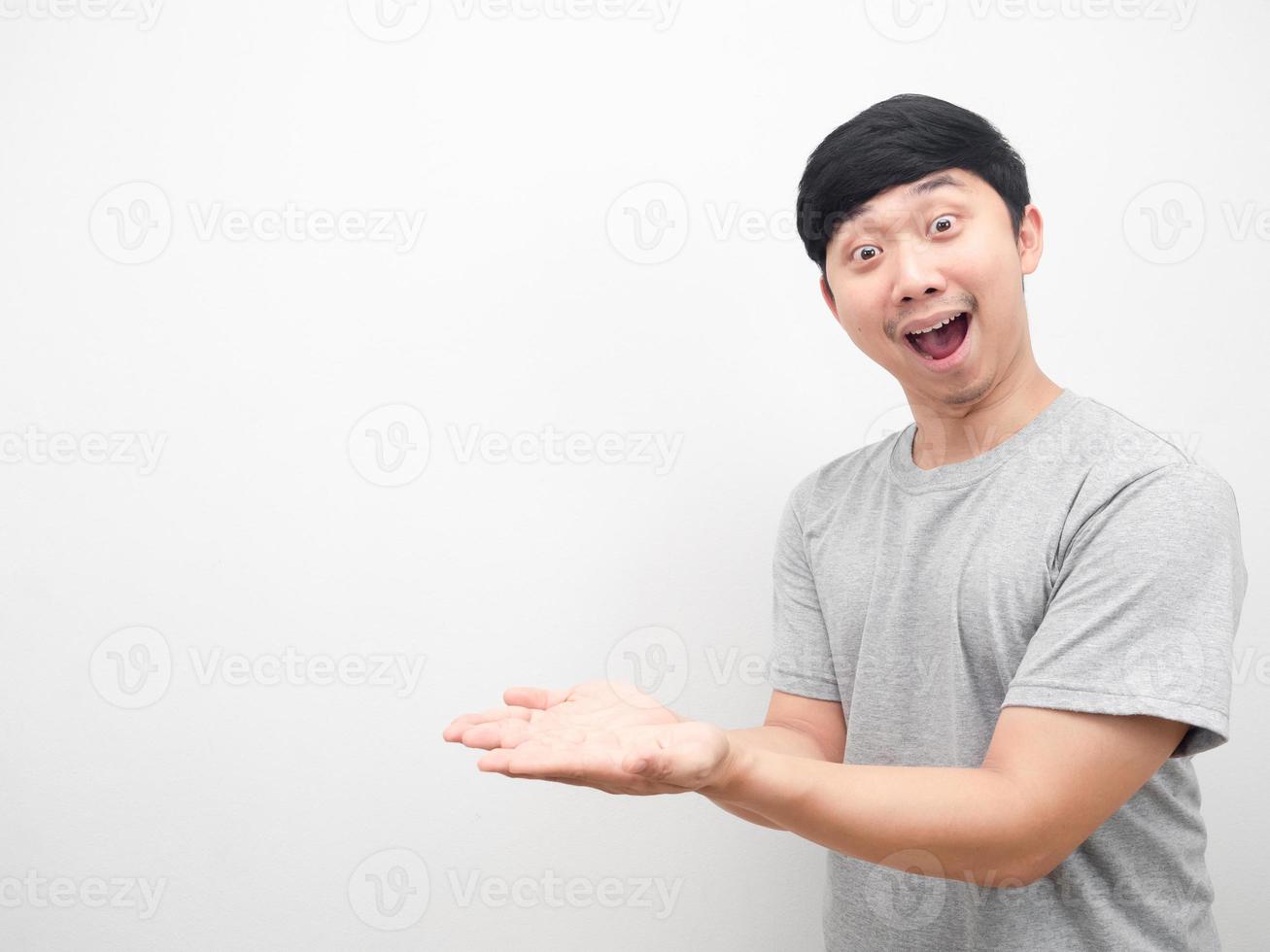 Cheerful asian man show empty hand for product concept copy space photo