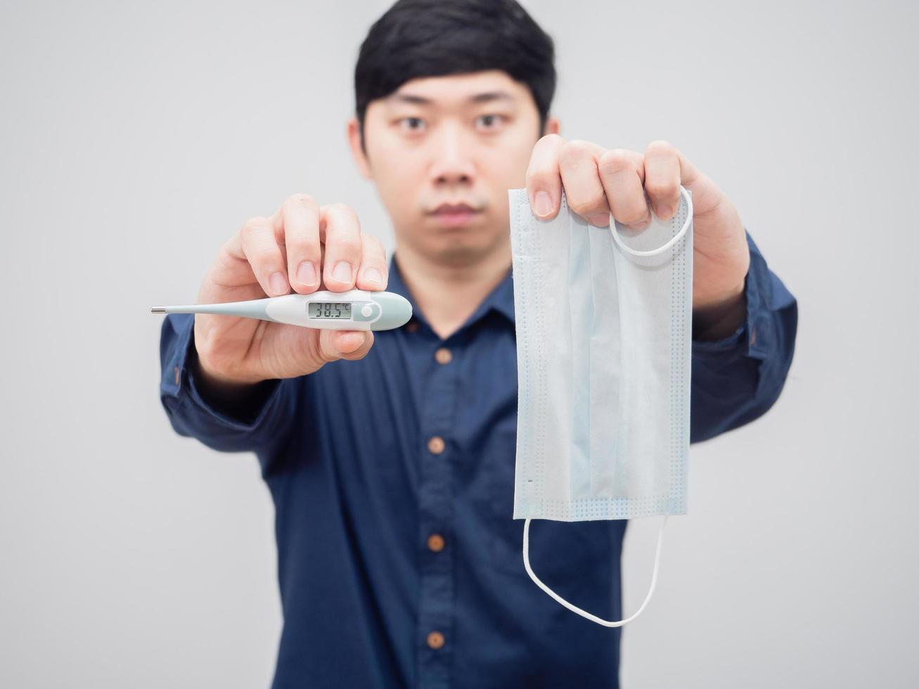 Closeup thermometer and mask in man hand on white background photo