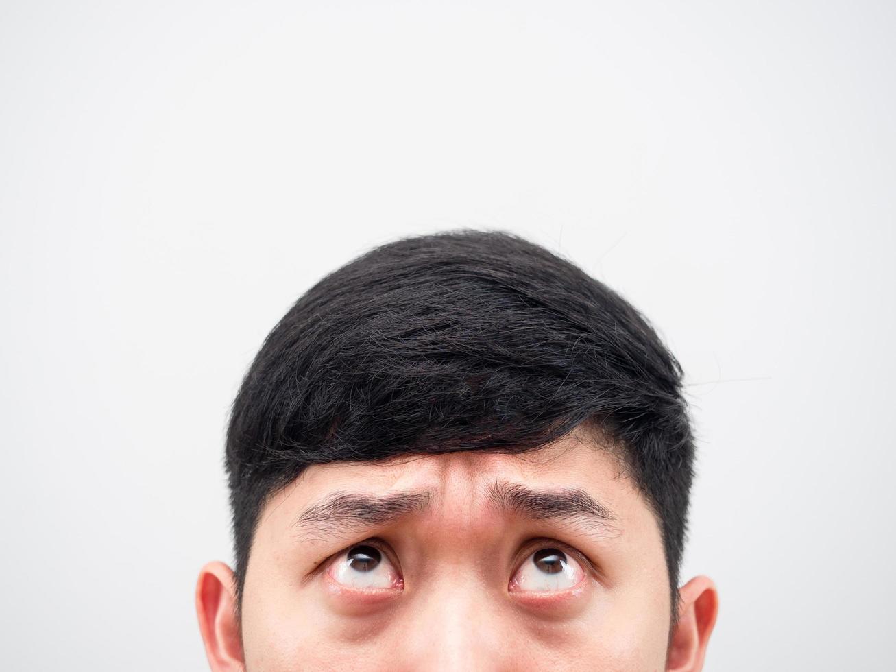 Closeup half face of man looking up feeling confused on white background copy space photo