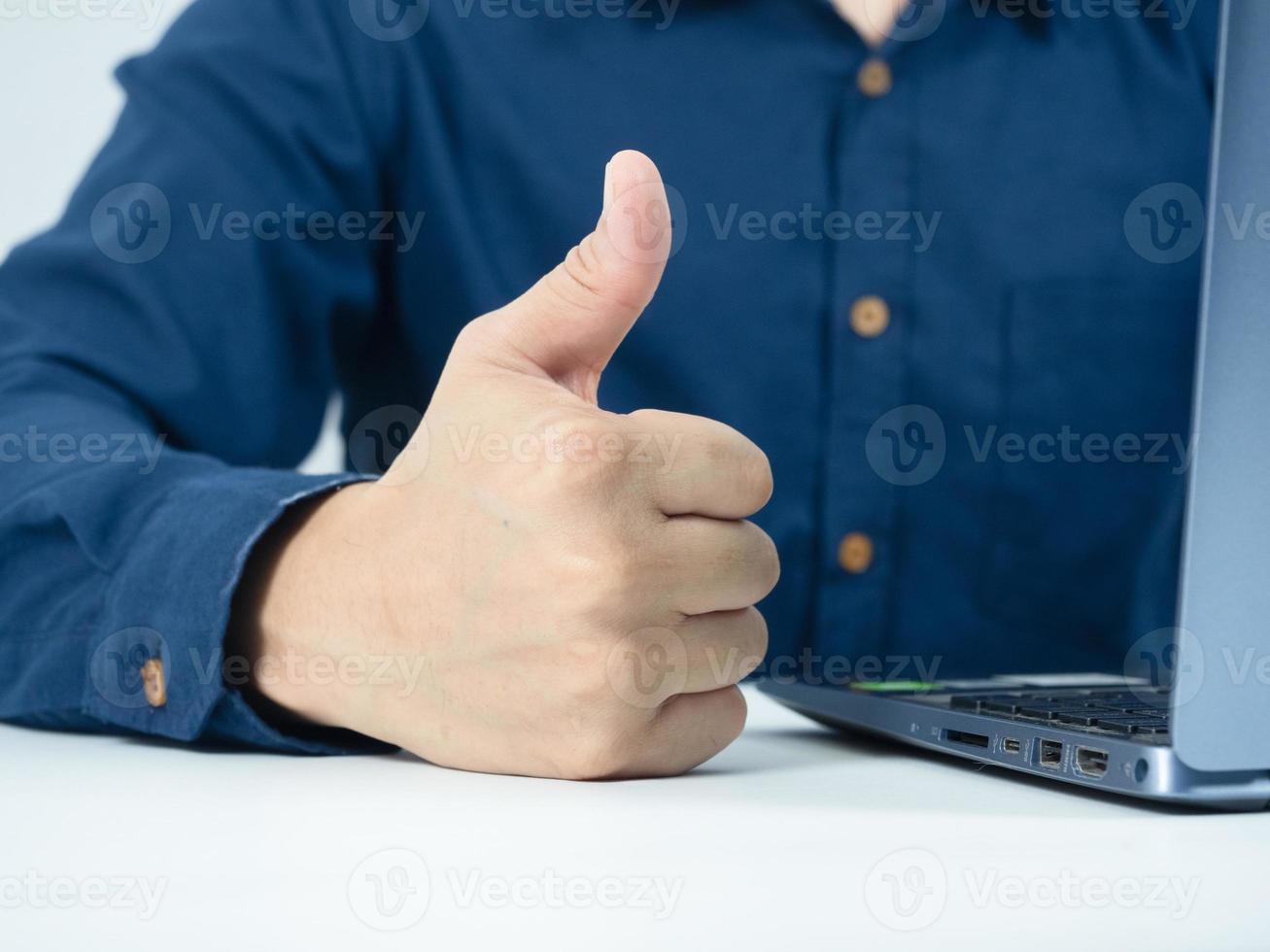 Man hand thumb up on the table with laptop in working room photo