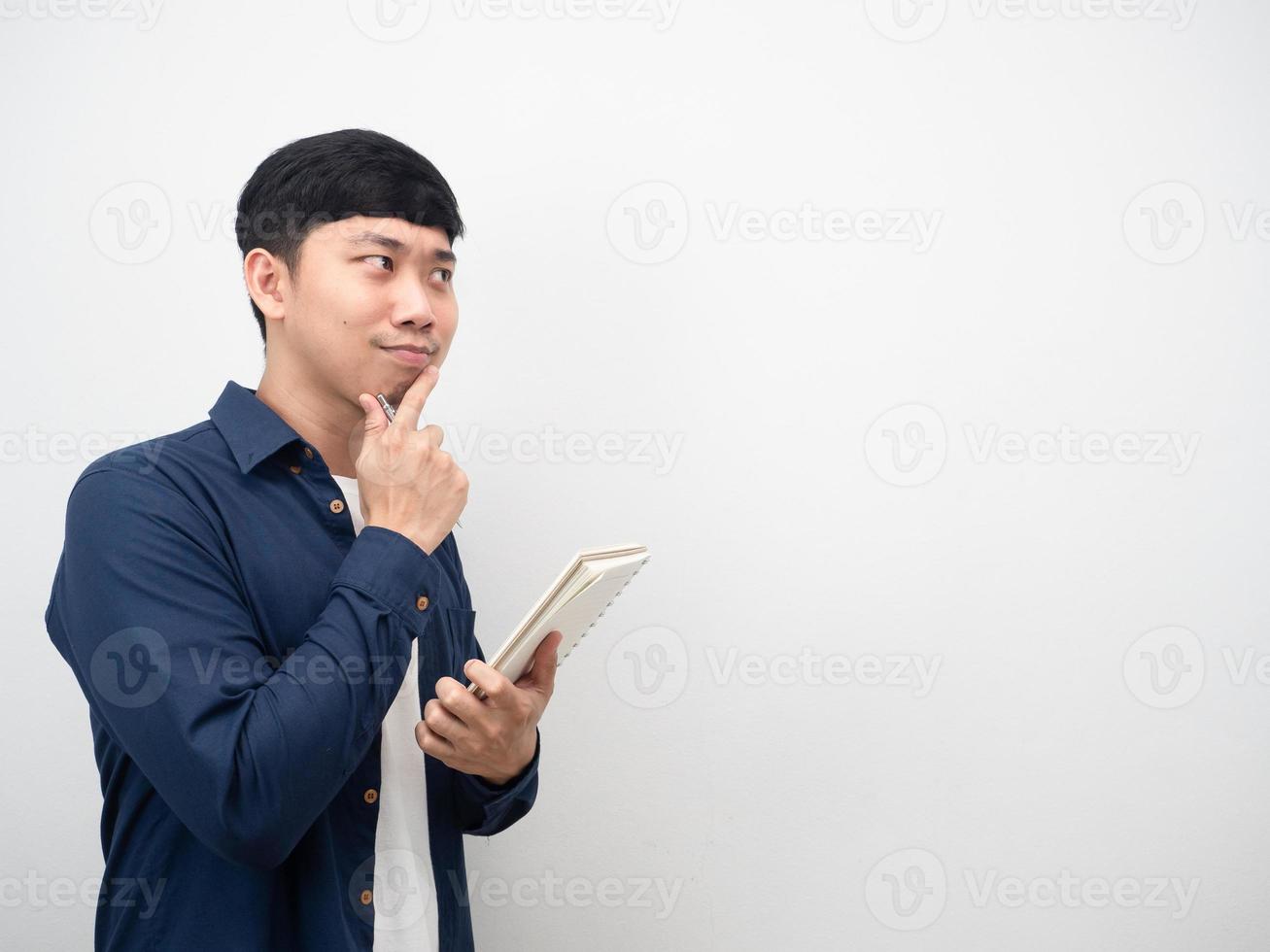 Man holding diary book gesture thinking and looking at copy space photo