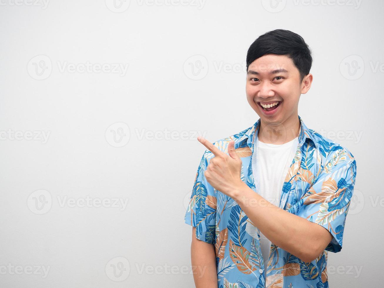 Cheerful man holiday shirt point finger at copy space with smile face photo