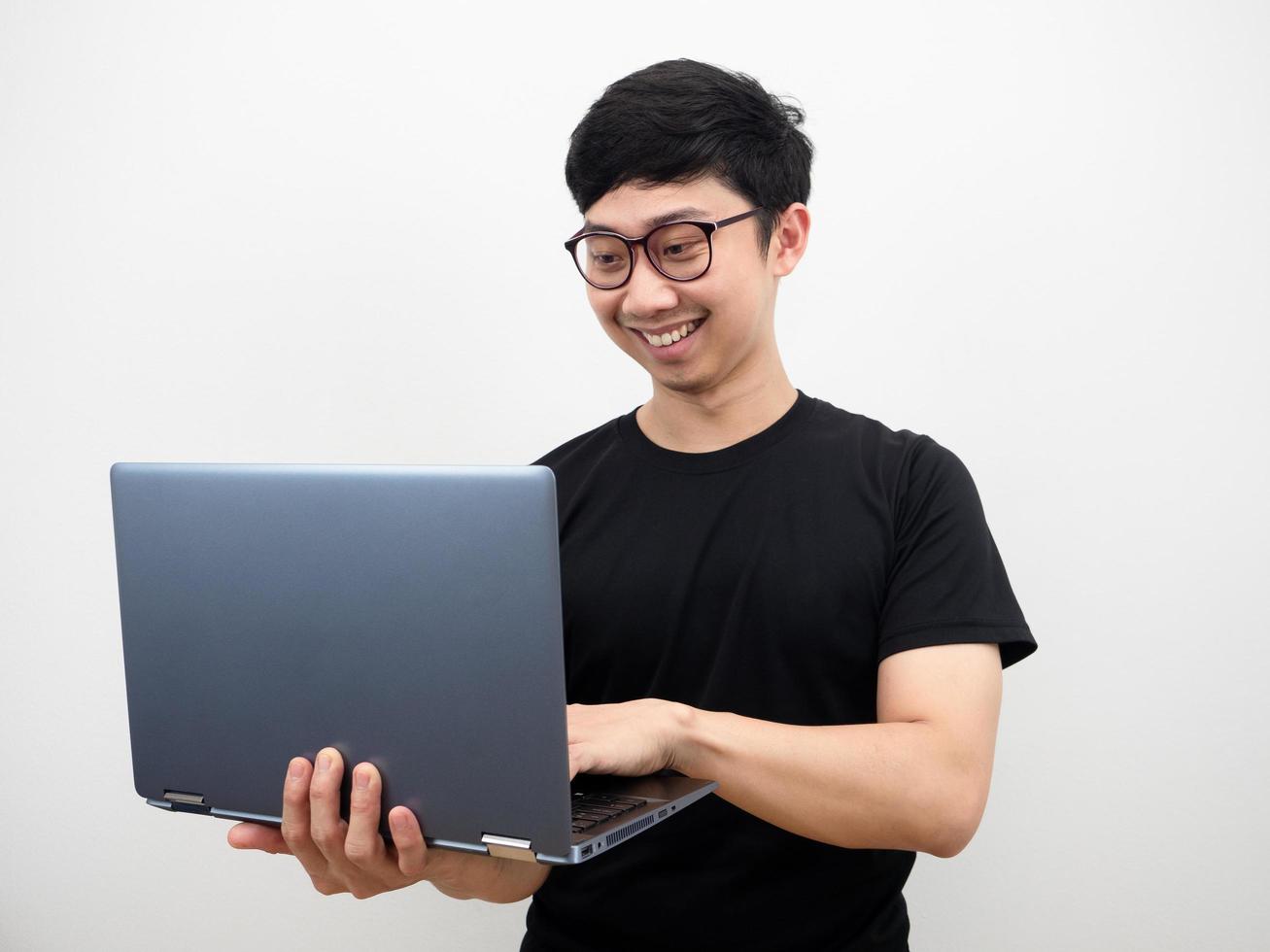 hombre con anteojos sosteniendo una laptop y trabajando con una sonrisa feliz en el fondo blanco foto