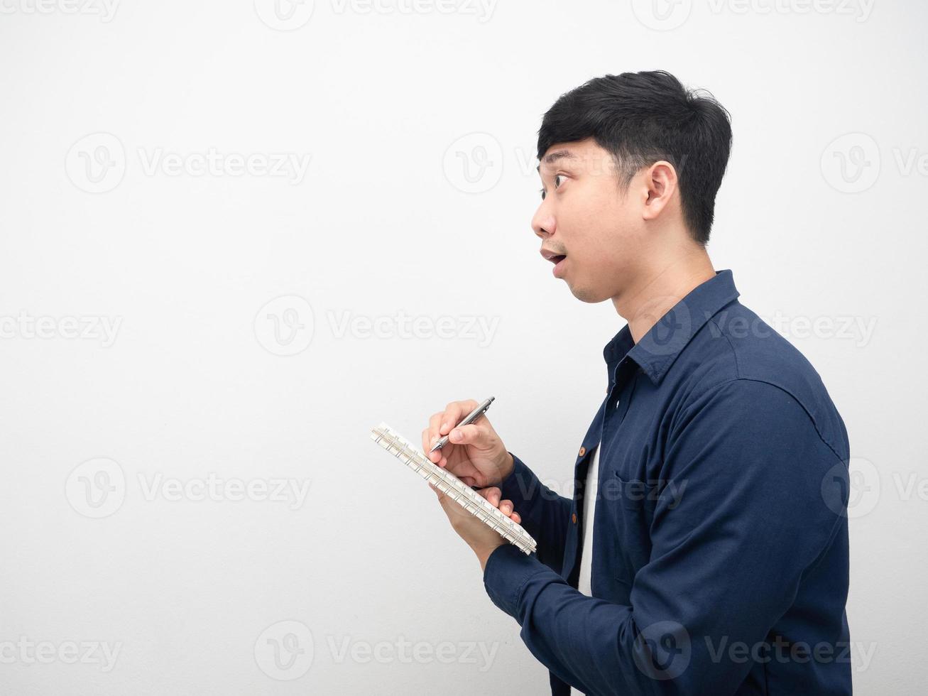Cheerful man writing on diary and looking at copy space side view photo