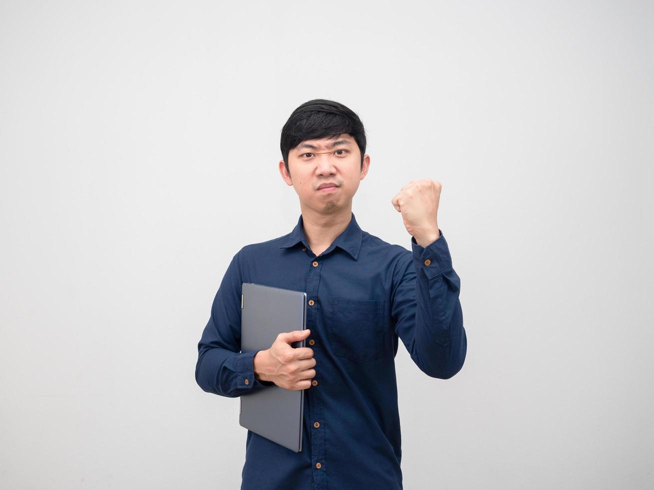 hombre de negocios asiático sosteniendo una computadora portátil y mostrando el puño en la cara confiada sobre fondo blanco foto