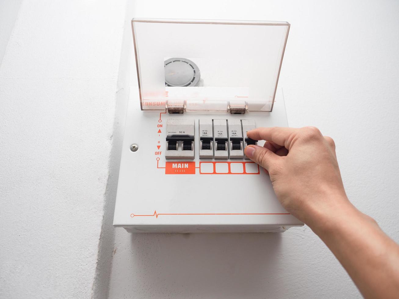 Hand checking electric safety breaker at the white wall in house,Mantainance electric breaker of house concept photo
