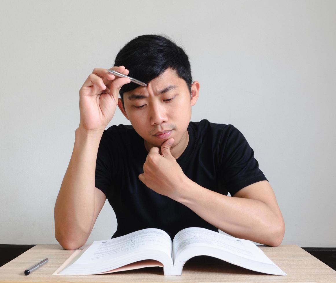 hombre serio con prueba, joven sentado en el escritorio y pensando con el libro en la mesa, concepto de prueba foto