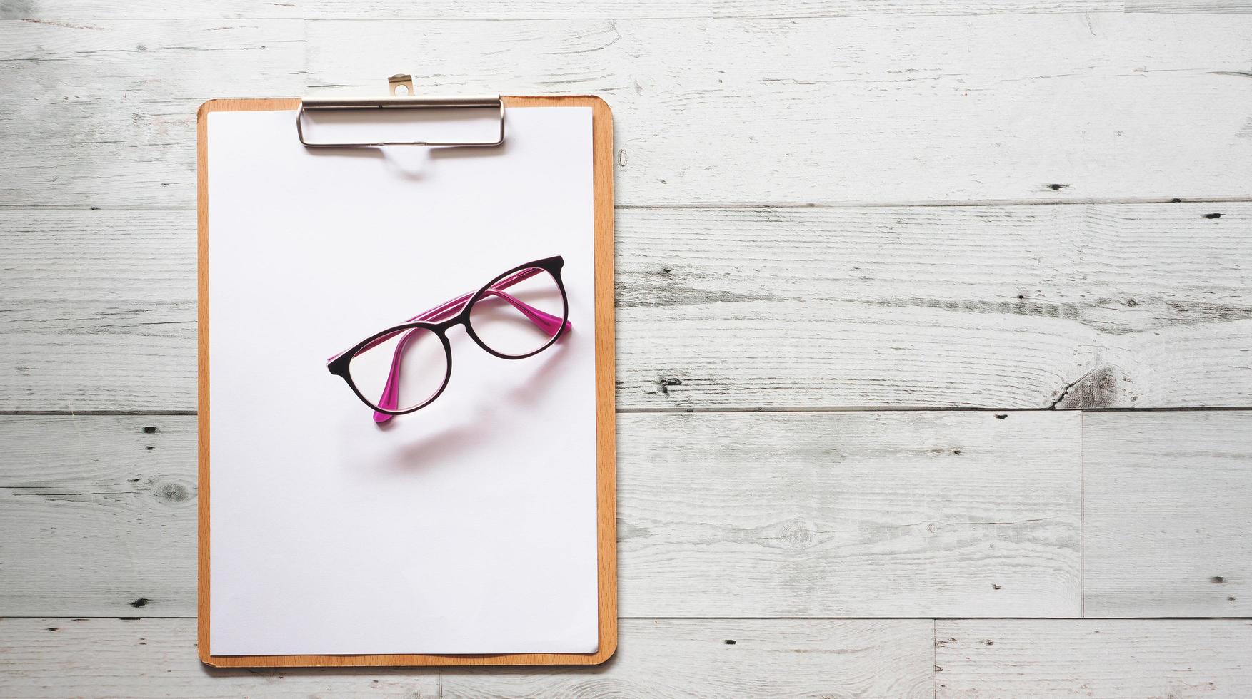 Glasses on blank document on wood clipboard on white wooden table background top view copy space,Business concept photo