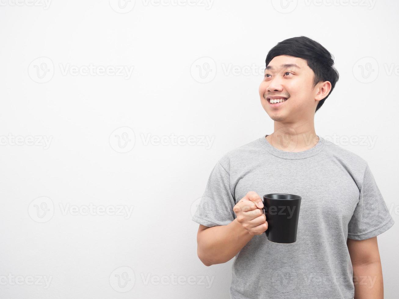 hombre sosteniendo una taza de café sonriendo y mirando el espacio de la copia foto