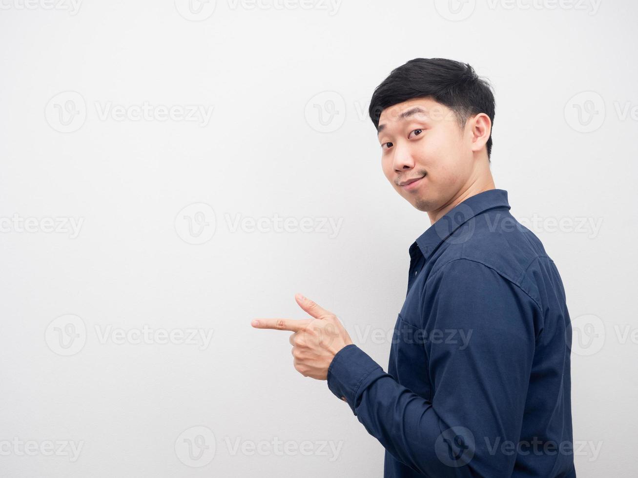 Man smile turn back and point finger at copy space photo