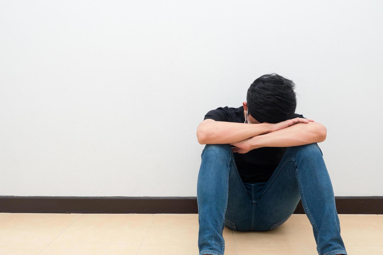 Man sit against the wall put head down feeling strain and sad emotion photo