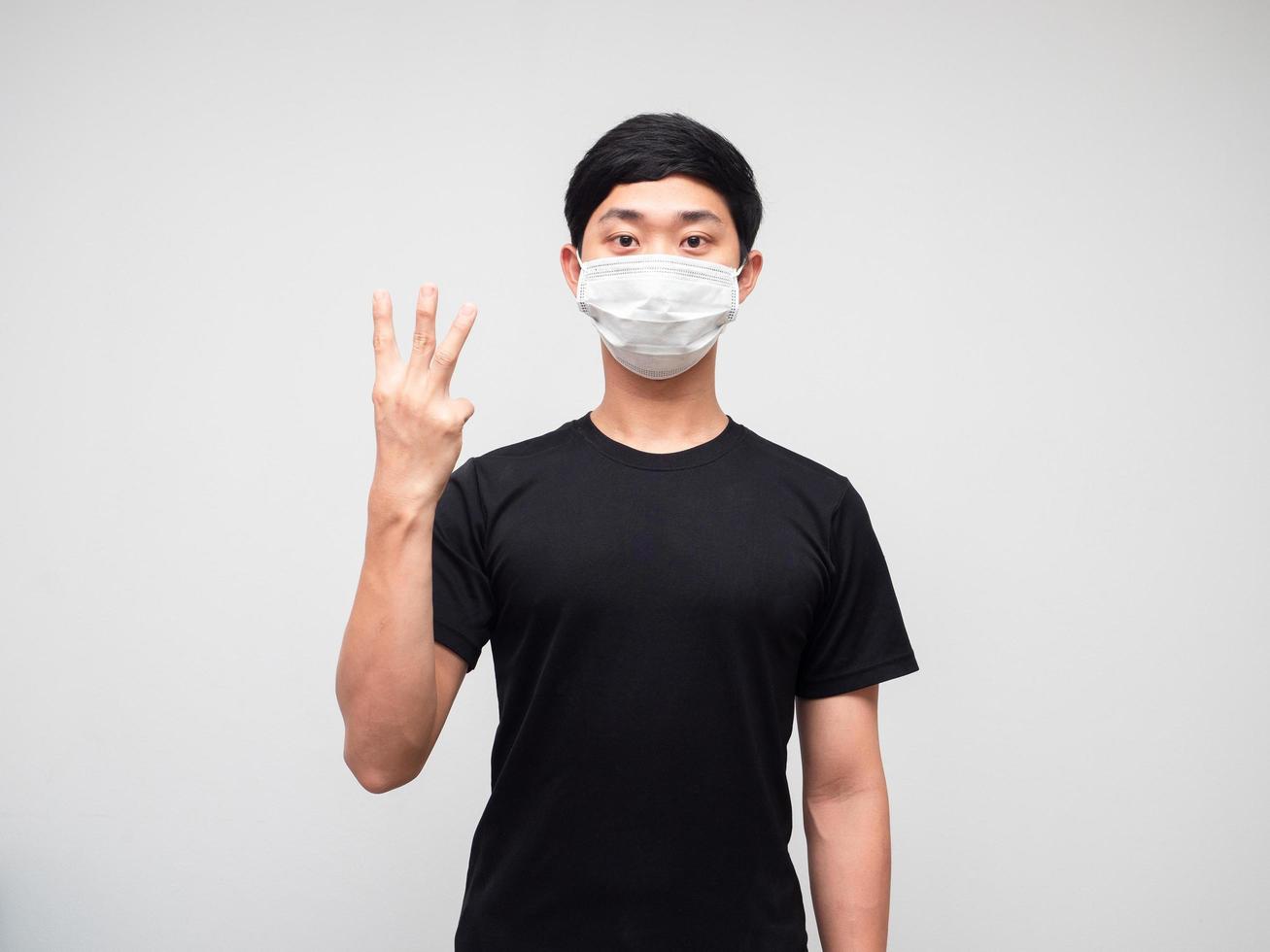 Asian man black shirt with mask show three finger counting on white isoated background photo