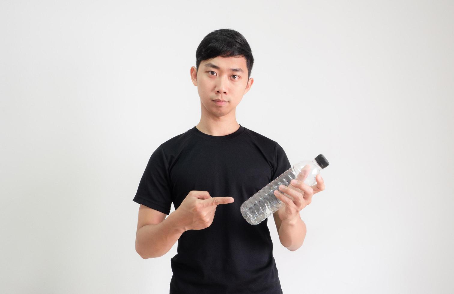 Young Asian man black shirt point finger at plastic bottle in hand with serious face look at camera on white isolated photo