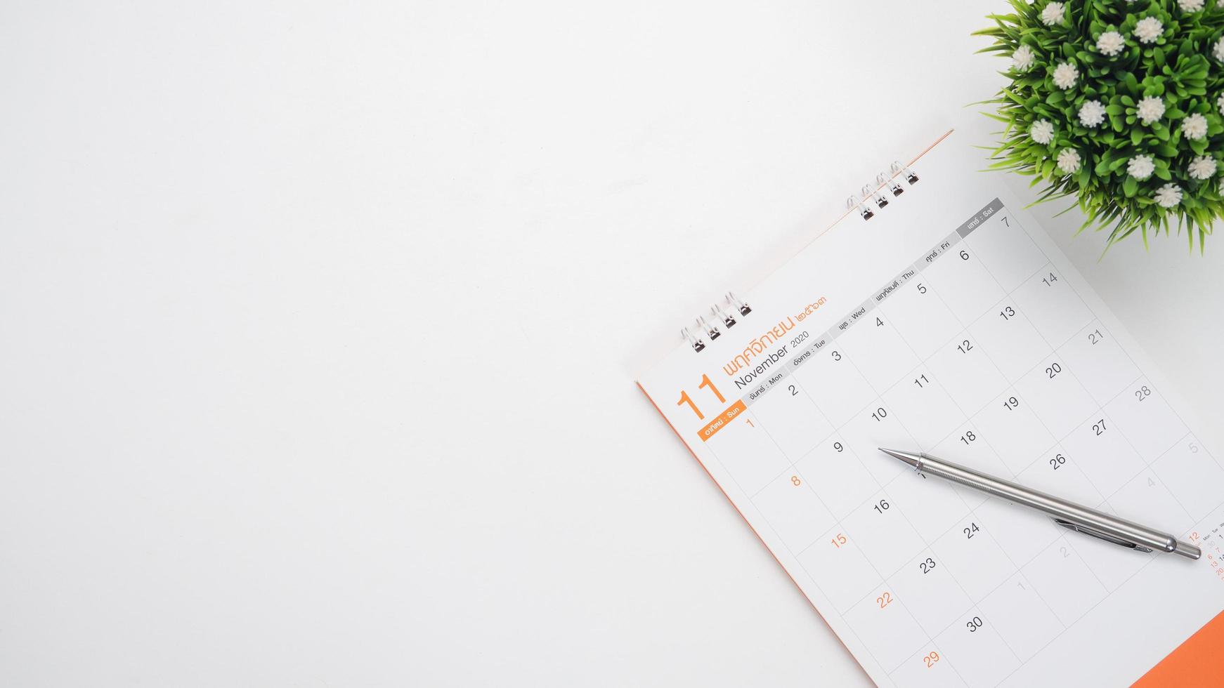 Calendar with vase and pen top view white background on the table copy space photo