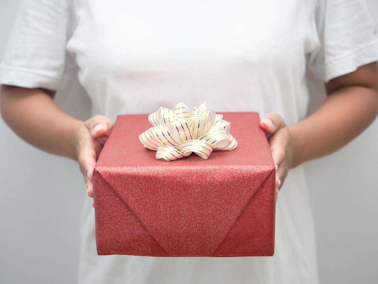 Close up woman hand giving red gift box white background photo