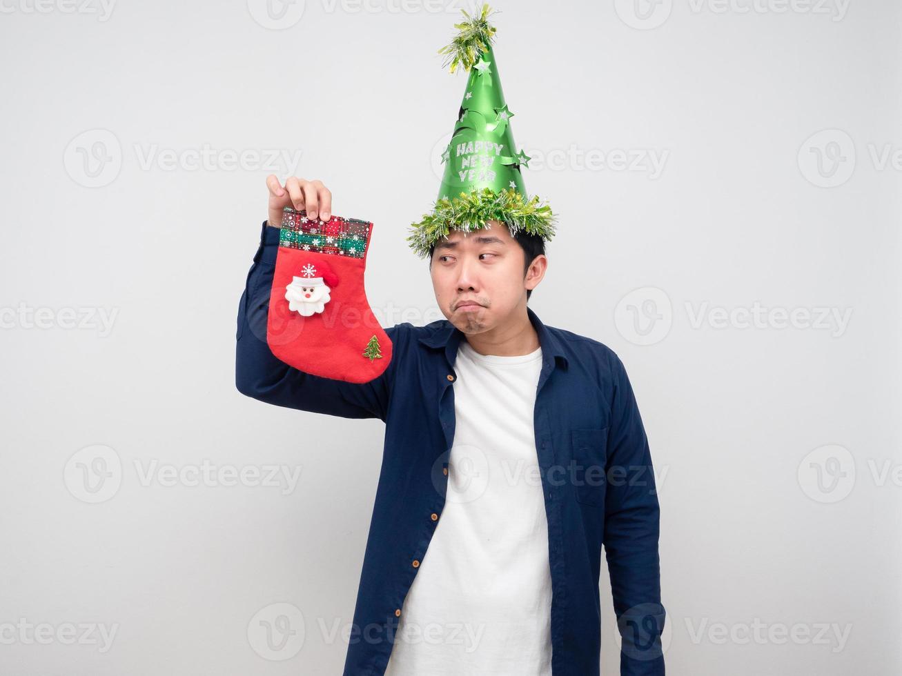 Man wearing green hat looking at chirstmas stocking in his hand photo