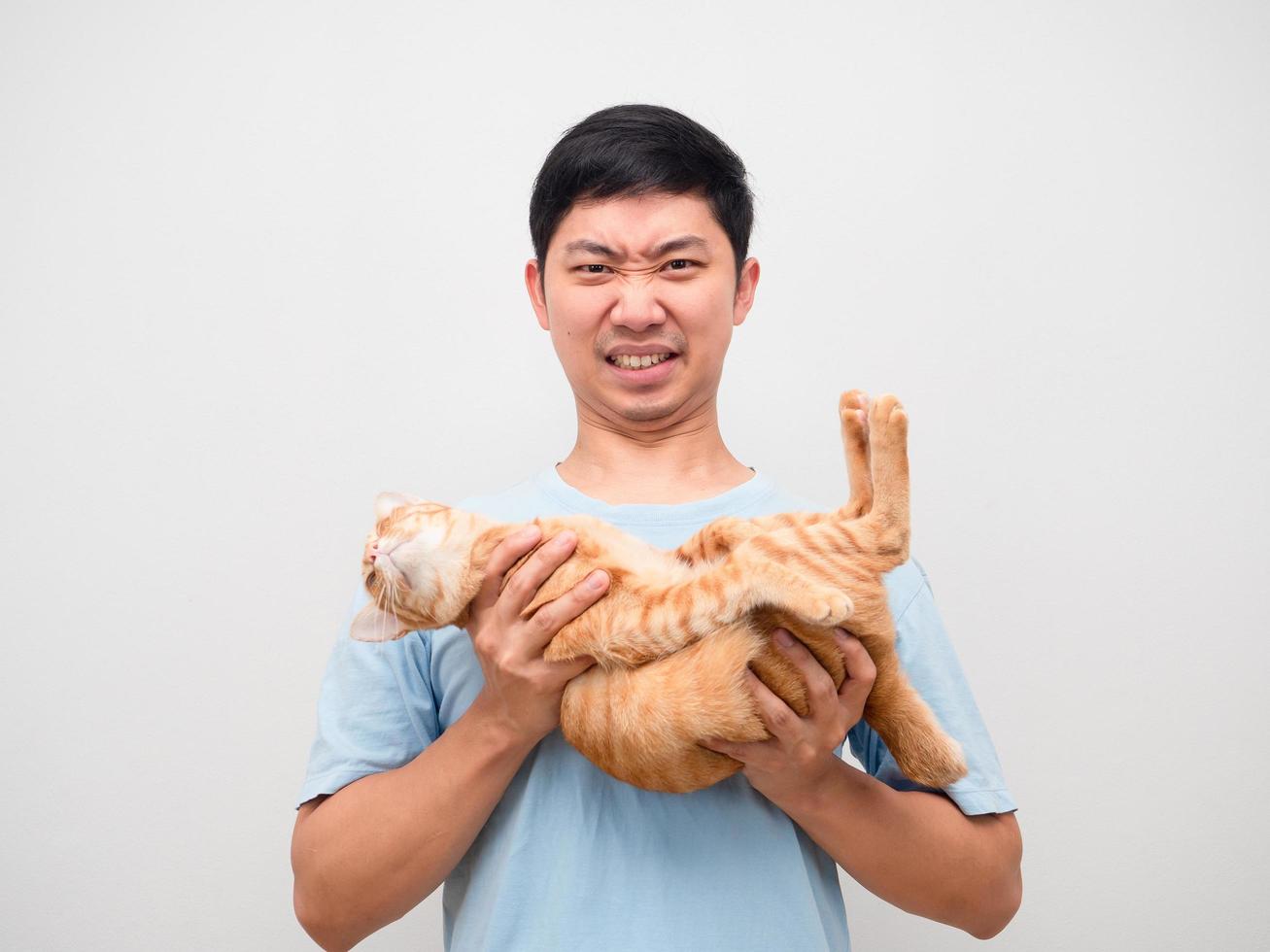Young man holding orange cat and feeling heavy on white background photo