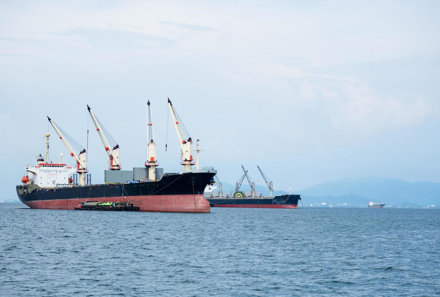 Big crane in the industrial ship in the ocean and mountain in island background,Transportation ship in economy sea concept landscape photo