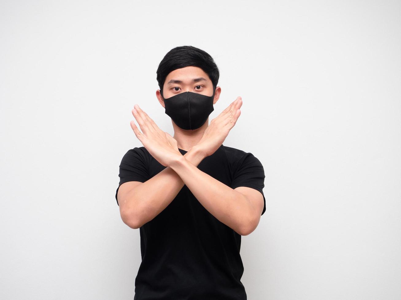 Asian man black shirt with mask cross arm disagree say no looking at camera on white isolate background photo