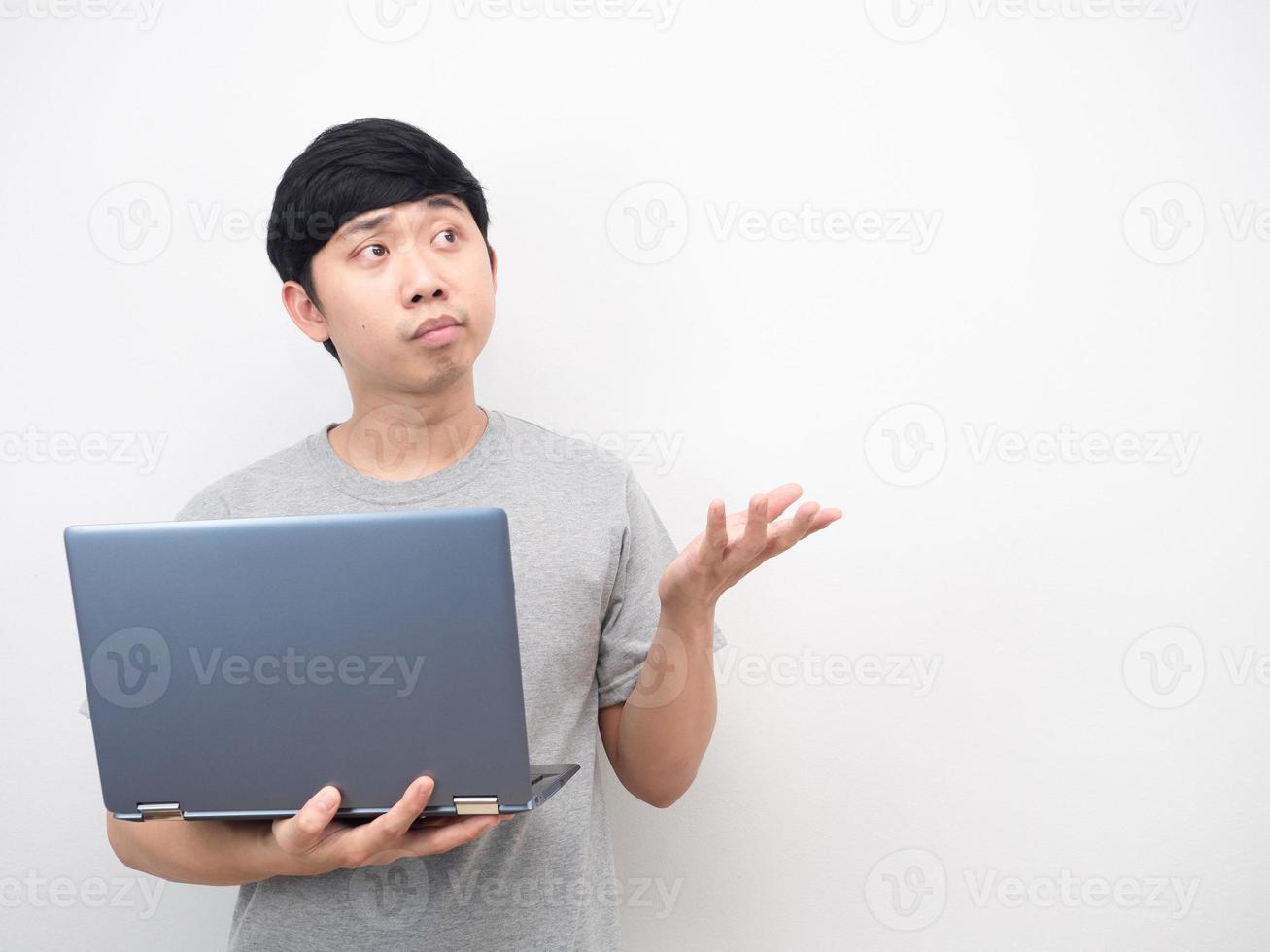 Asian man holding laptop gesture bored point hand at copy space photo