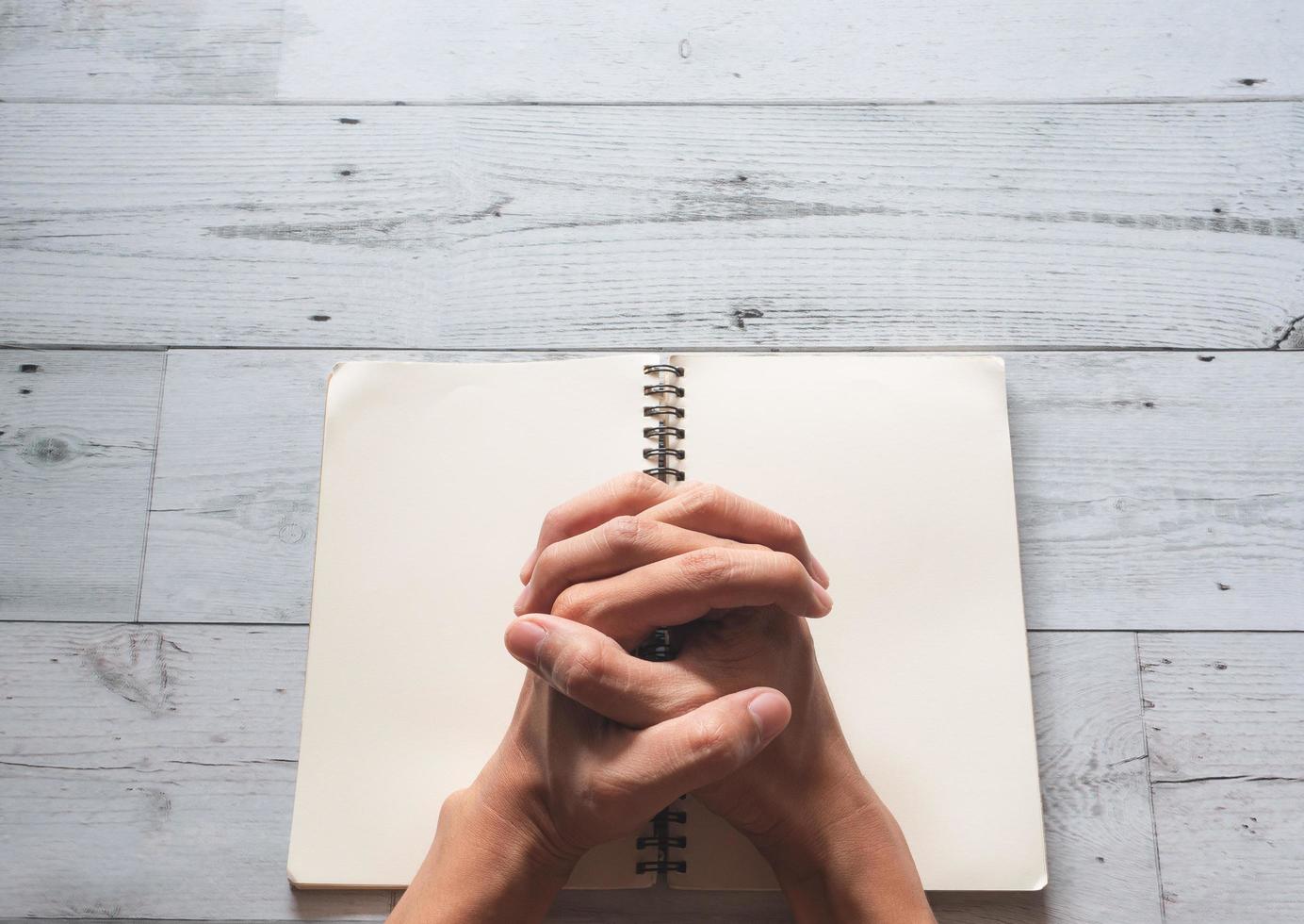 Praying hands on book blank page and sunlight nature shadow on white wooden texture background top view,Pray god concept photo