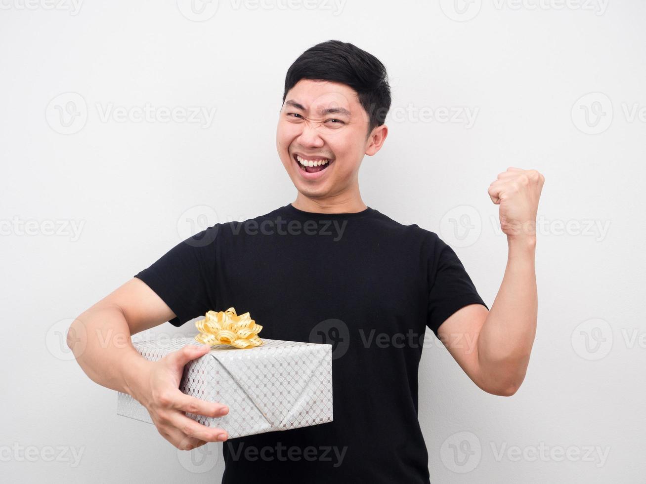 Happy man holding gift box and fist up photo