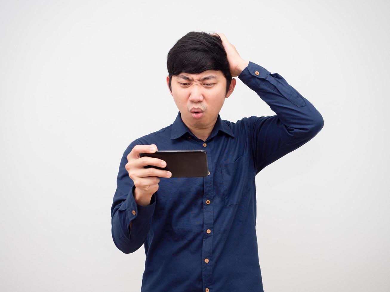 hombre asiático jugando en el teléfono móvil sintiéndose aburrido tocar su cabeza fondo blanco foto