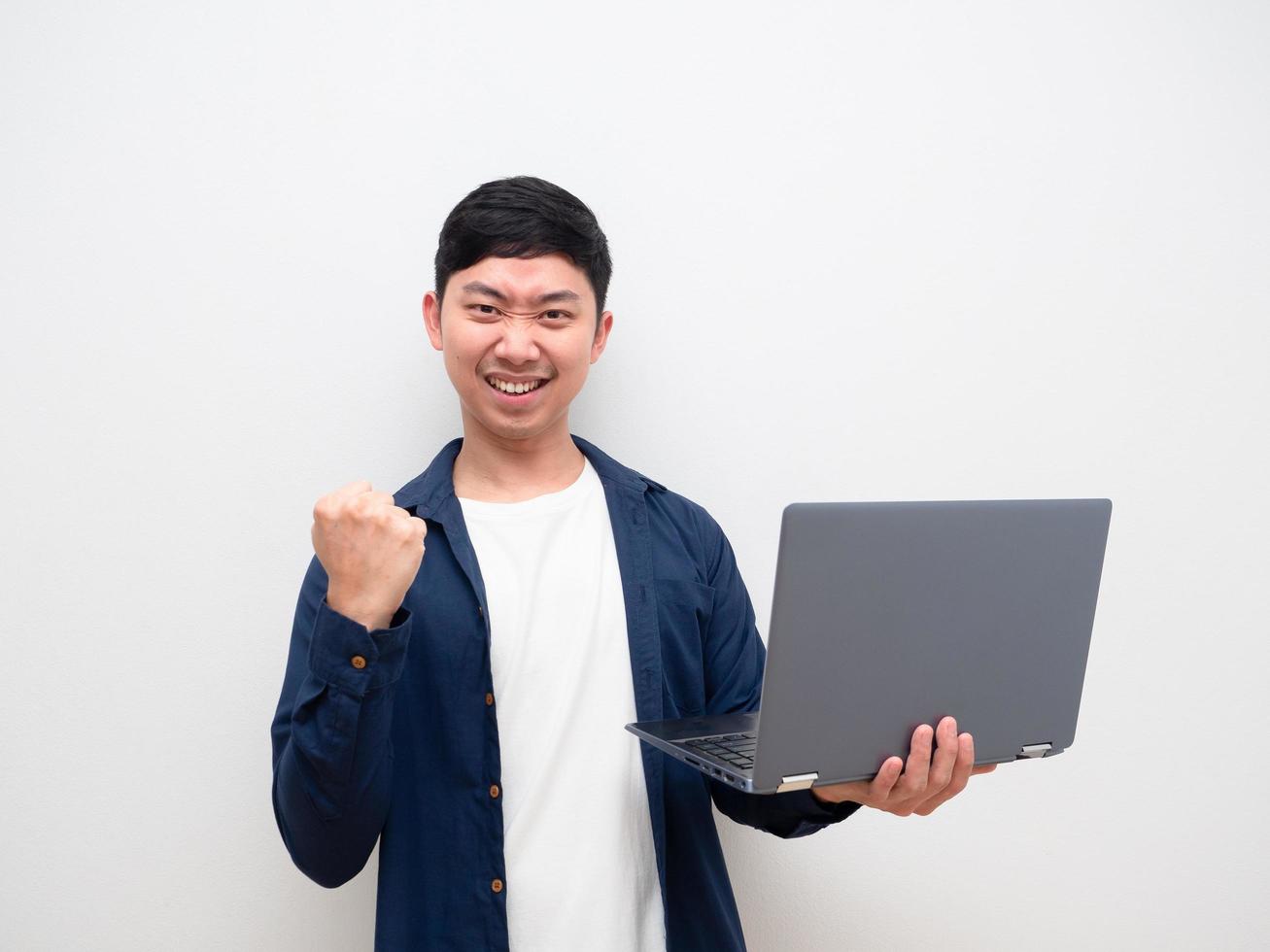 Handsome man holding laptop show fist up confident face look at camera on white background photo