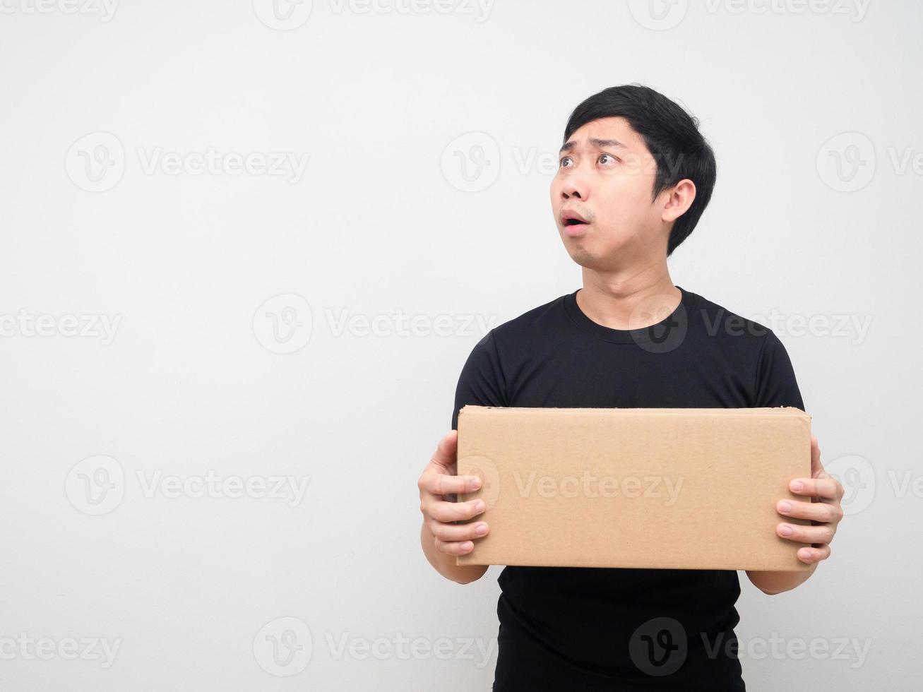 Man feeling shocked and holding box in hand and looking at copy space photo