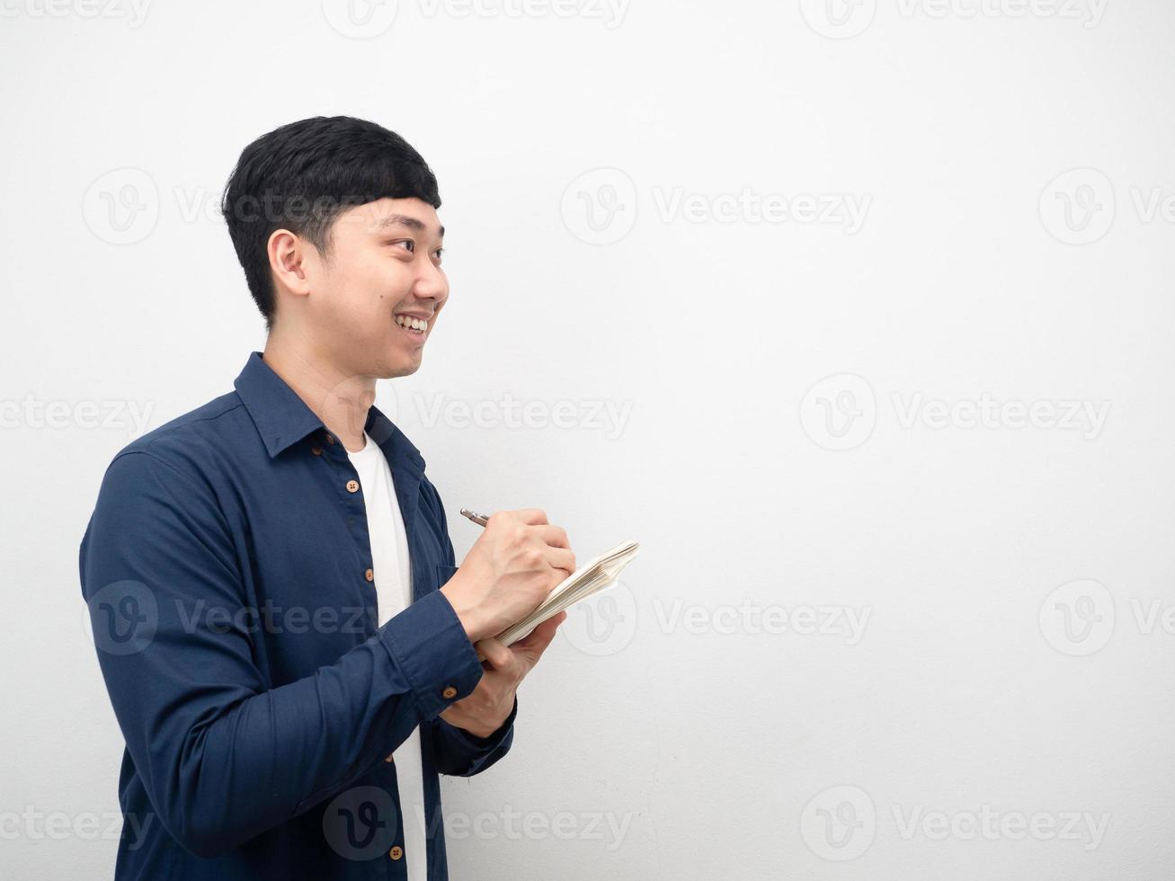 Asian man note in diary book with smiling and looking at copy space side view photo